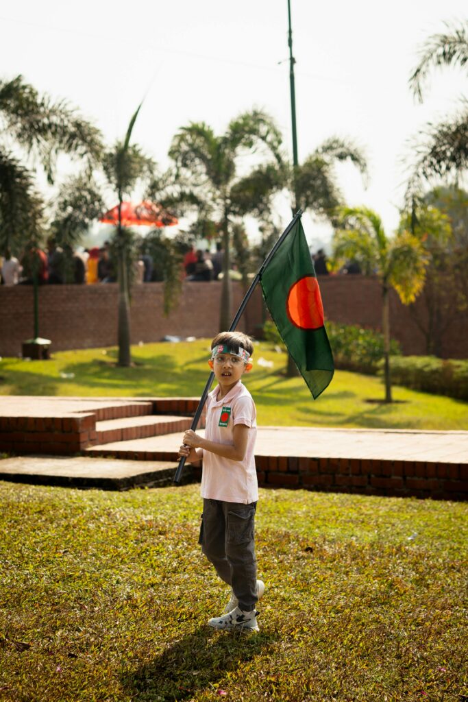 pexels-photo-35432712-35432712 A young boy enthusiastically waves the Bangladesh flag during Victory Day celebrations in Dhaka.